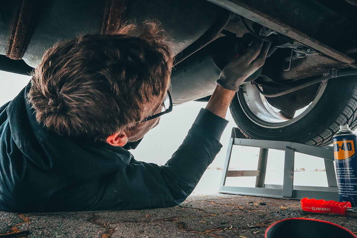 Mechanic performing maintenance on the underside of a vehicle